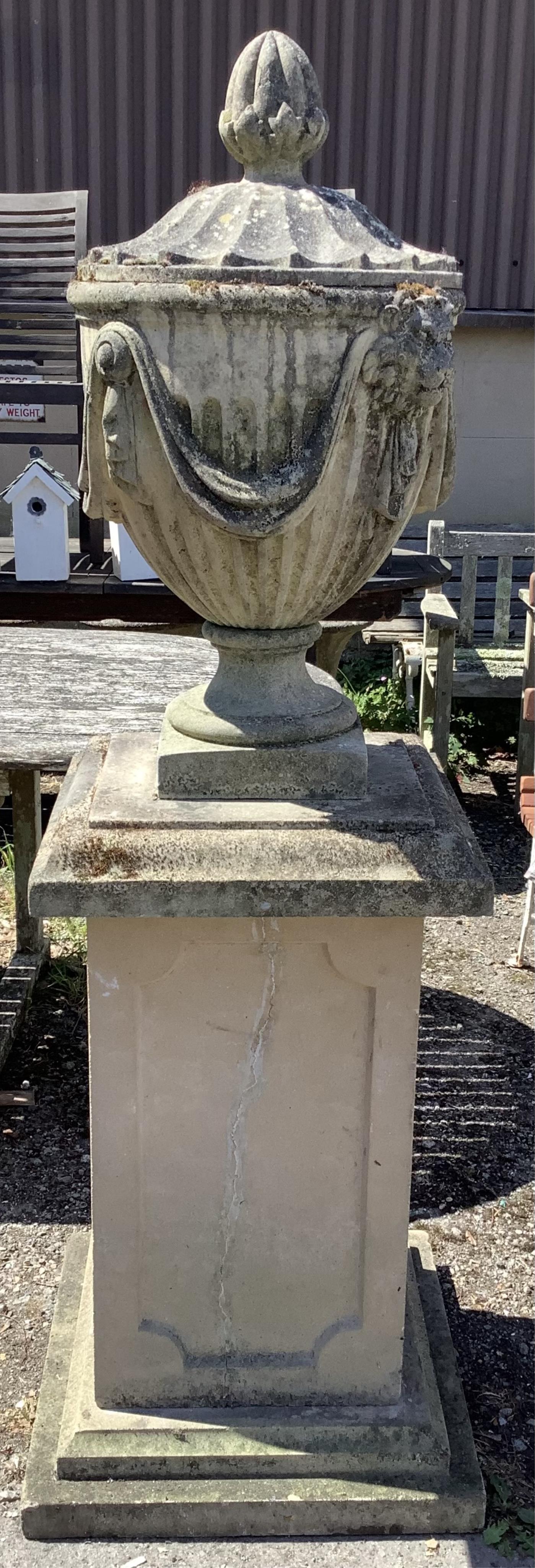 A reconstituted stone Adam style lidded garden urn on a square pedestal base, height 160cm